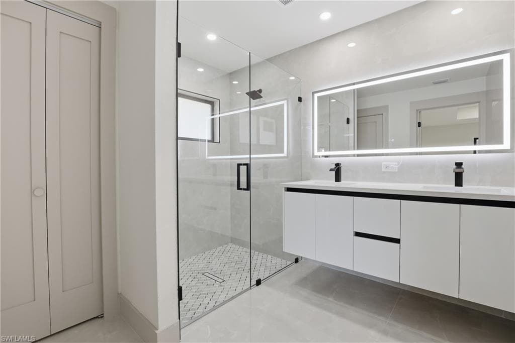 Full bathroom featuring double vanity, a shower stall, a closet, and recessed lighting