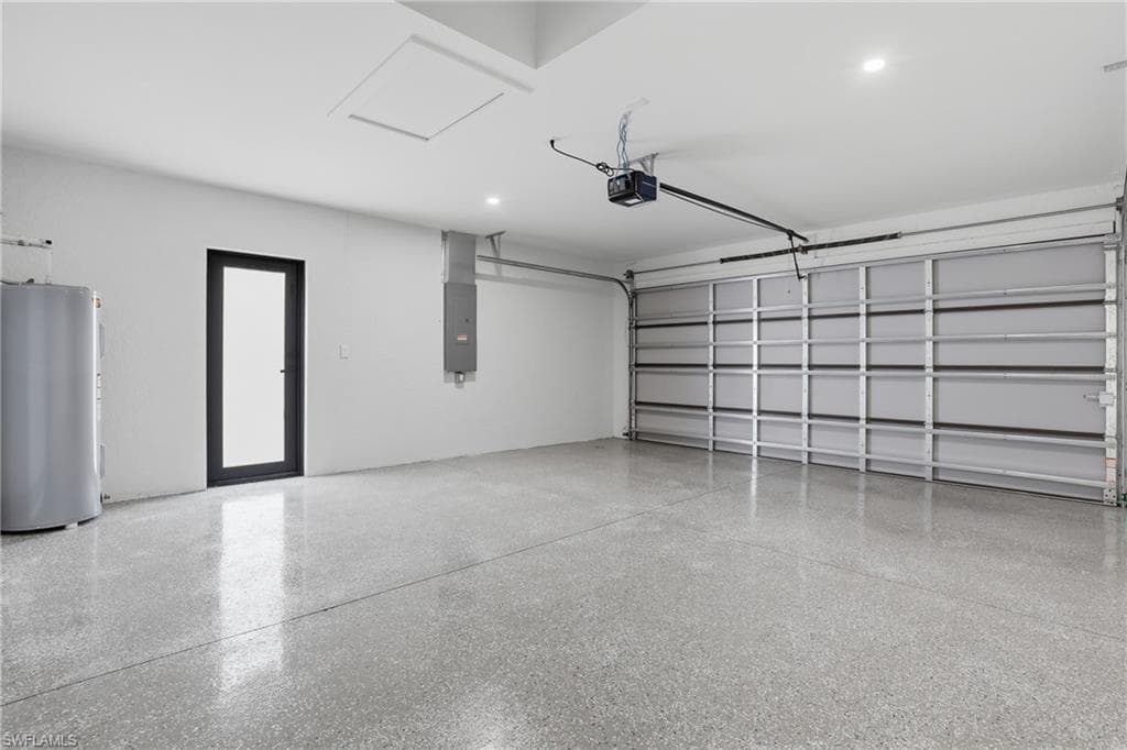 Garage featuring water heater, electric panel, and a garage door opener
