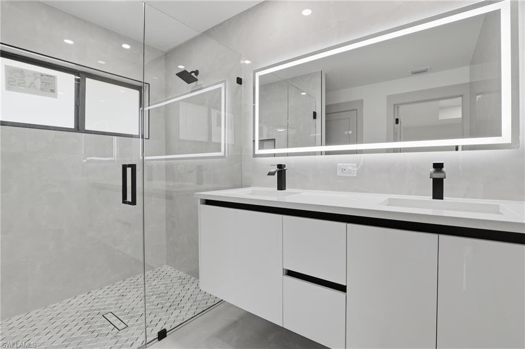 Bathroom featuring double vanity, a shower stall, and recessed lighting