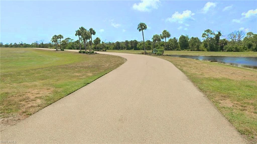 Surrounding community with a yard, view of wooded area, and a water view