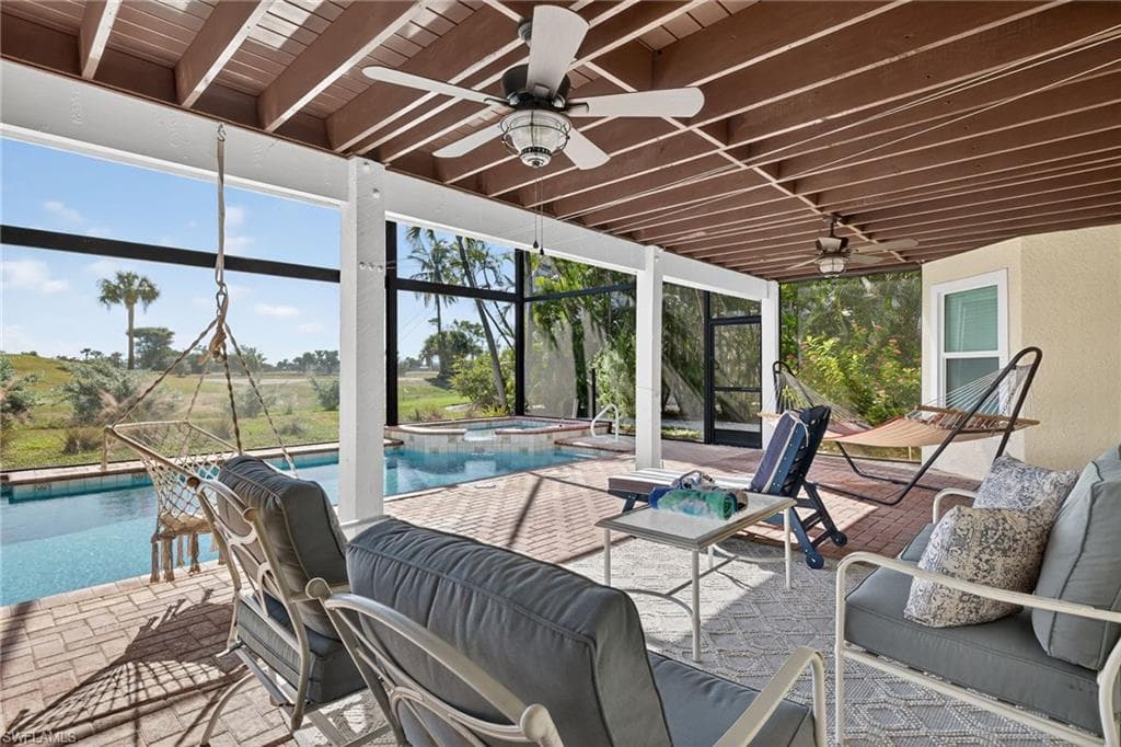 View of patio with a lanai, a pool with connected hot tub, a ceiling fan, and outdoor lounge area