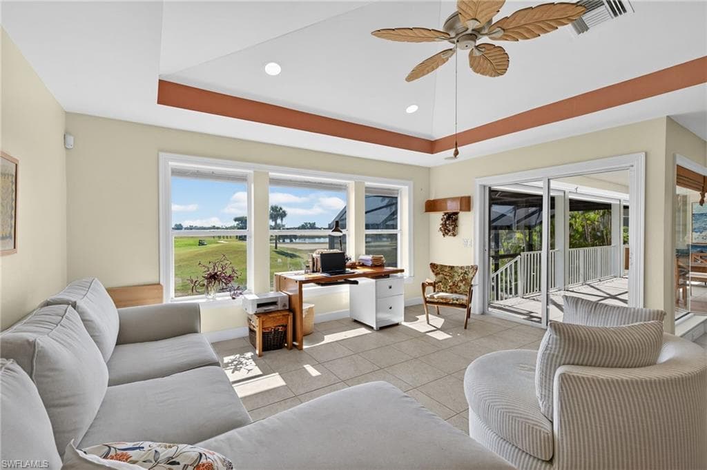 Living room featuring tile patterned flooring, ceiling fan, a tray ceiling, recessed lighting, and an office area