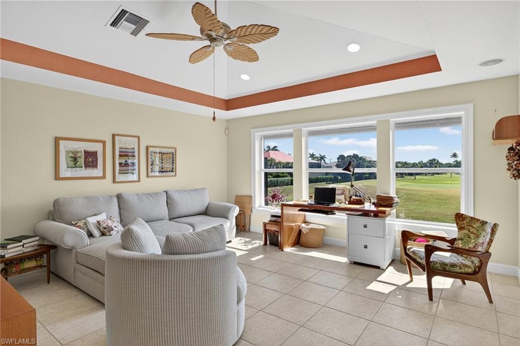 Living area featuring light tile patterned flooring, a raised ceiling, a desk, a ceiling fan, and recessed lighting