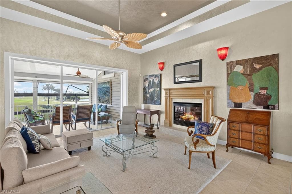 Tiled living area featuring a raised ceiling, a premium fireplace, crown molding, a sunroom, and recessed lighting