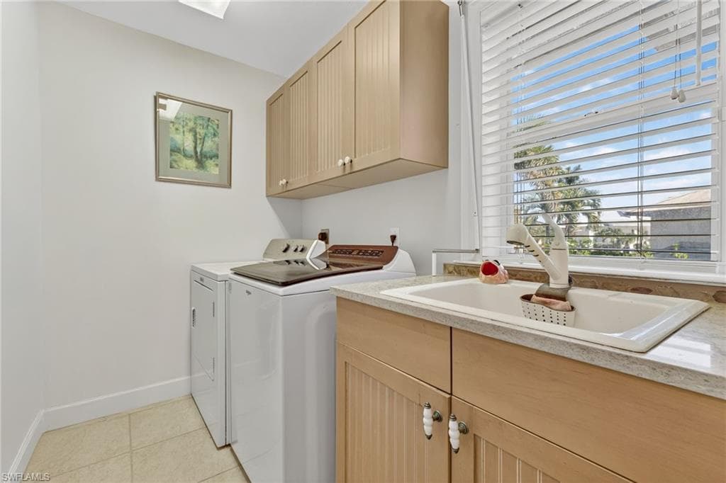 Washroom featuring cabinet space, light tile patterned floors, and washing machine and clothes dryer