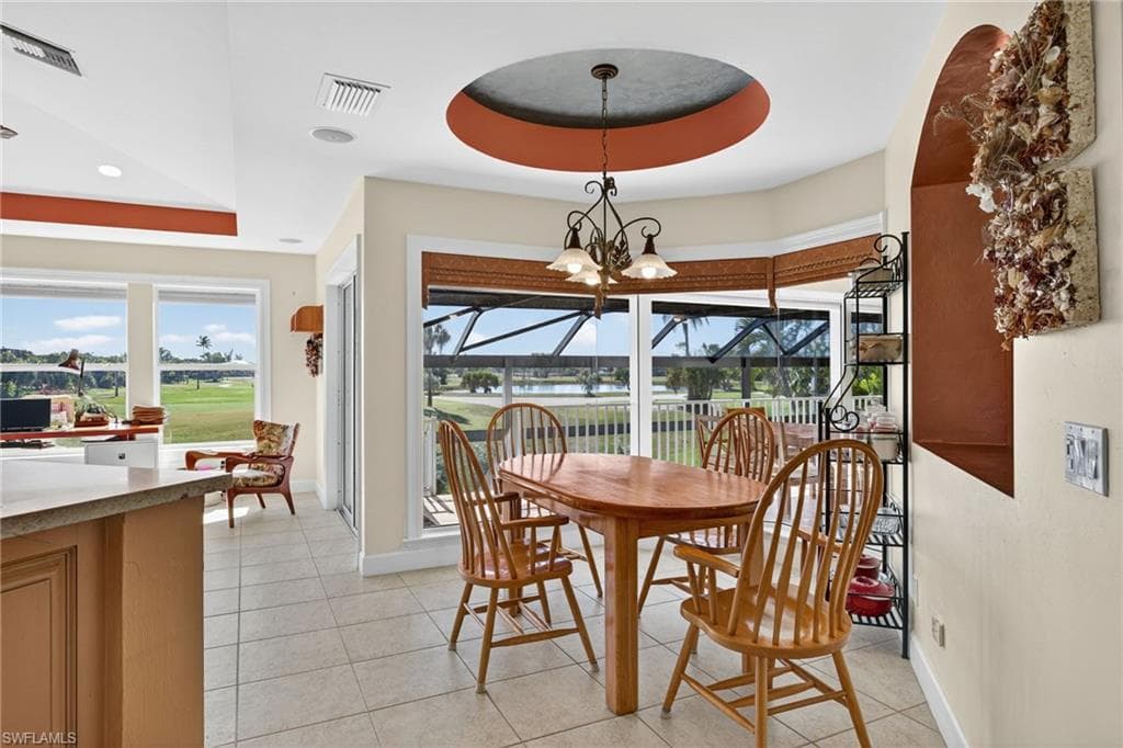Dining room with a sunroom, healthy amount of natural light, a tray ceiling, light tile patterned floors, and recessed lighting