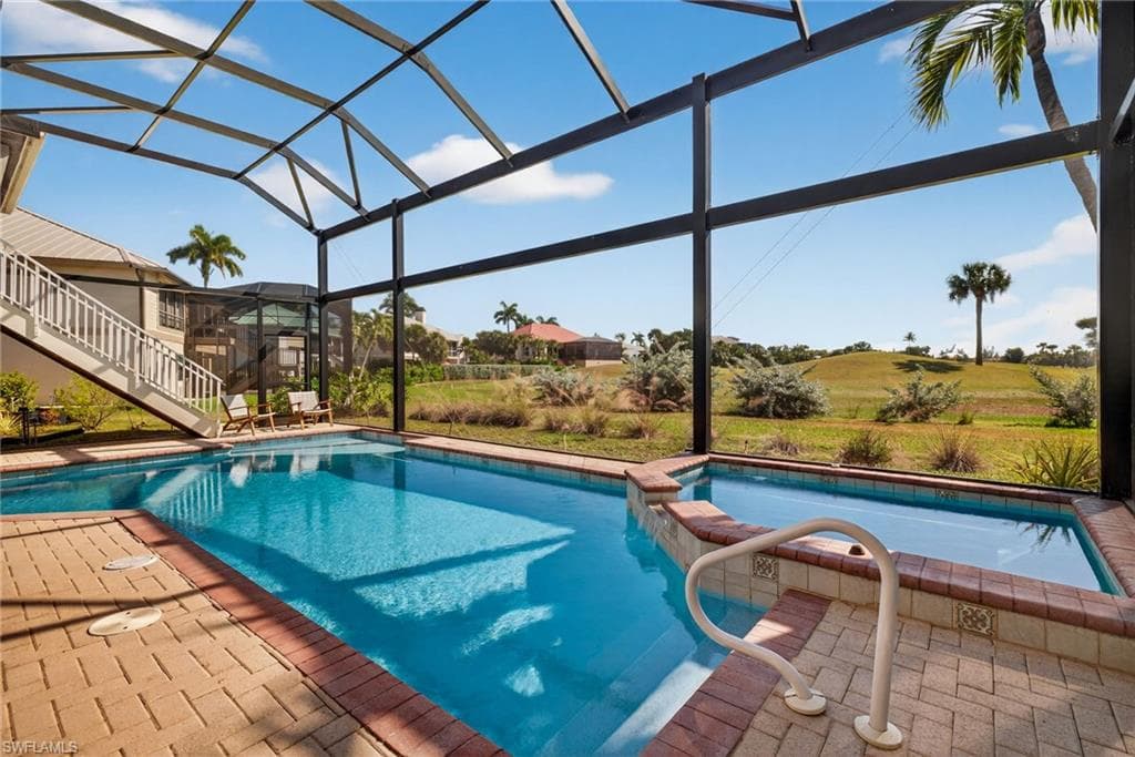 View of swimming pool with a lanai, a patio area, a sunroom, stairs, and a pool with connected hot tub
