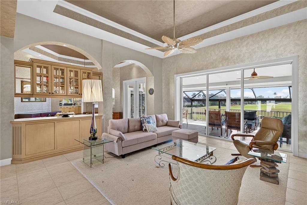 Living area featuring a tray ceiling, light tile patterned flooring, and a sunroom