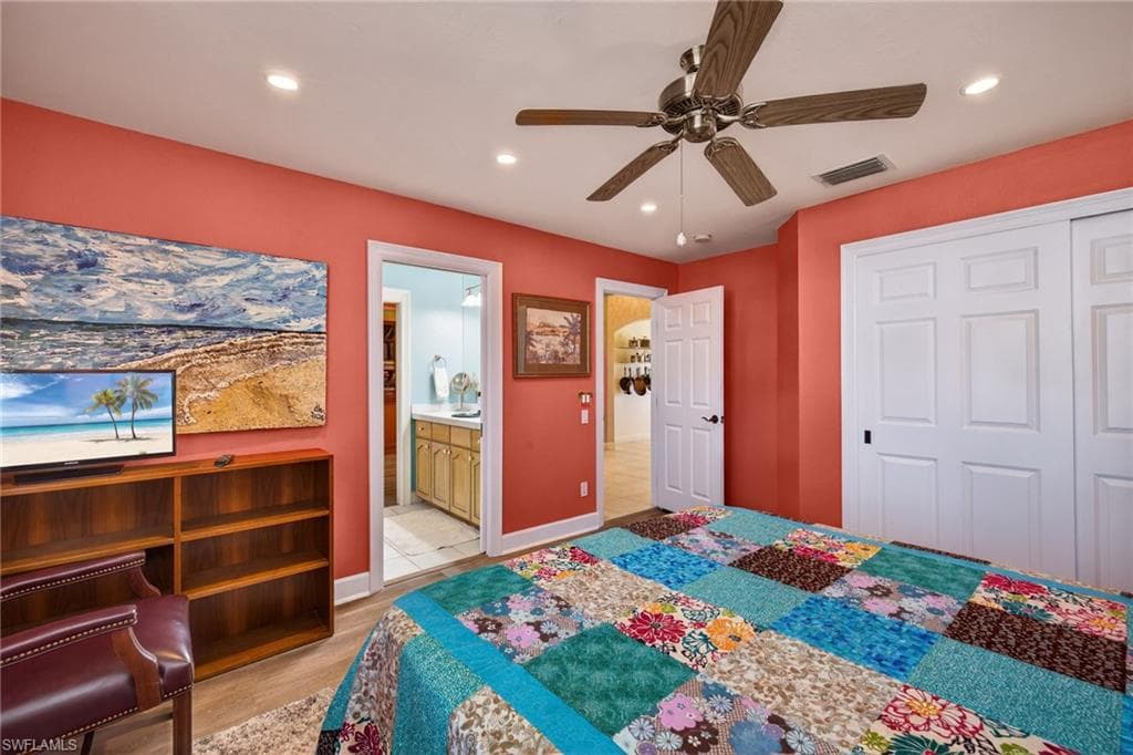Bedroom featuring recessed lighting, light wood-style flooring, a ceiling fan, ensuite bathroom, and a closet