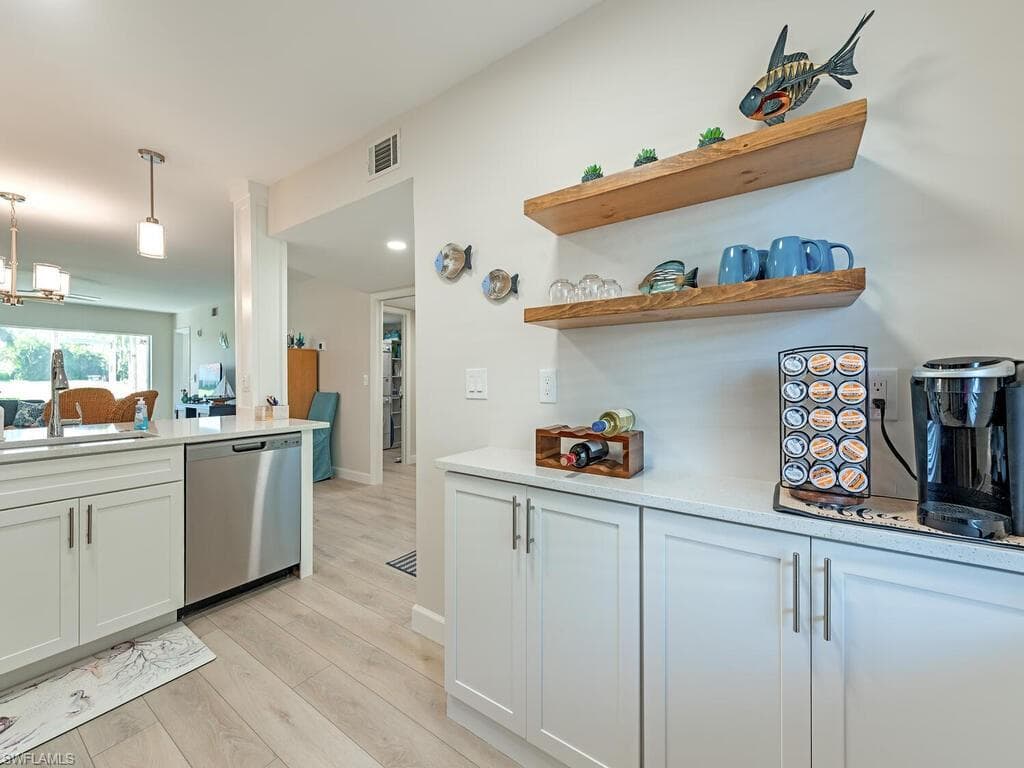 Kitchen with white cabinets, open shelves, light stone counters, stainless steel dishwasher, and recessed lighting