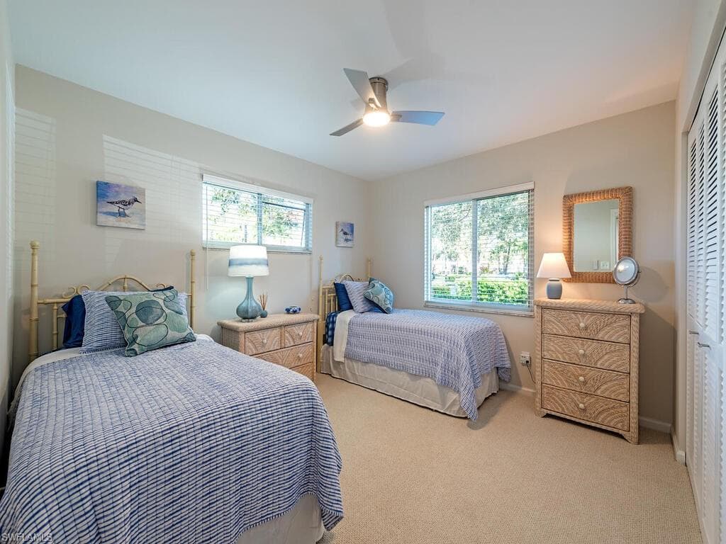 Bedroom with light carpet, multiple windows, and ceiling fan