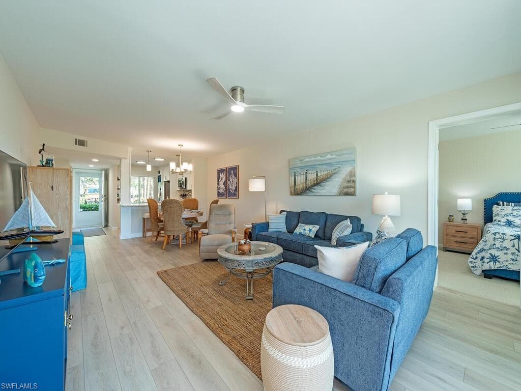 Living area featuring a chandelier, light wood-style floors, and a ceiling fan
