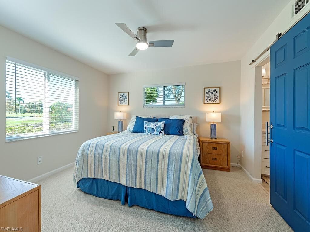Bedroom featuring a barn door, light colored carpet, and ceiling fan