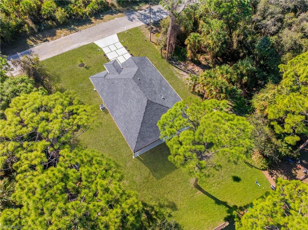 Aerial view of property and surrounding area featuring a tree filled landscape