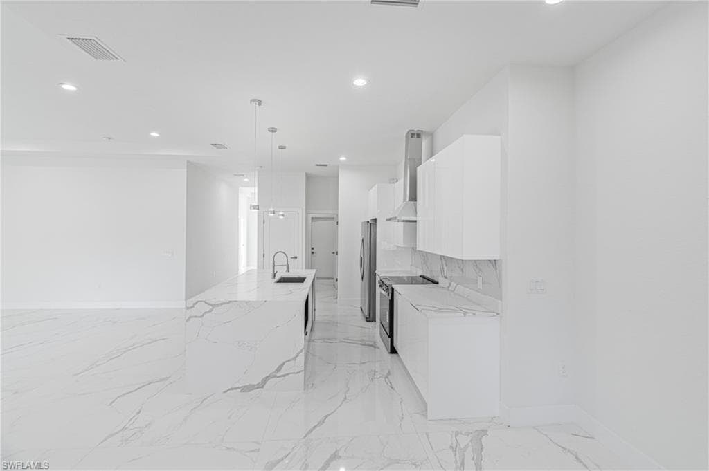 Kitchen with white cabinetry, stainless steel appliances, light stone counters, modern cabinets, and recessed lighting