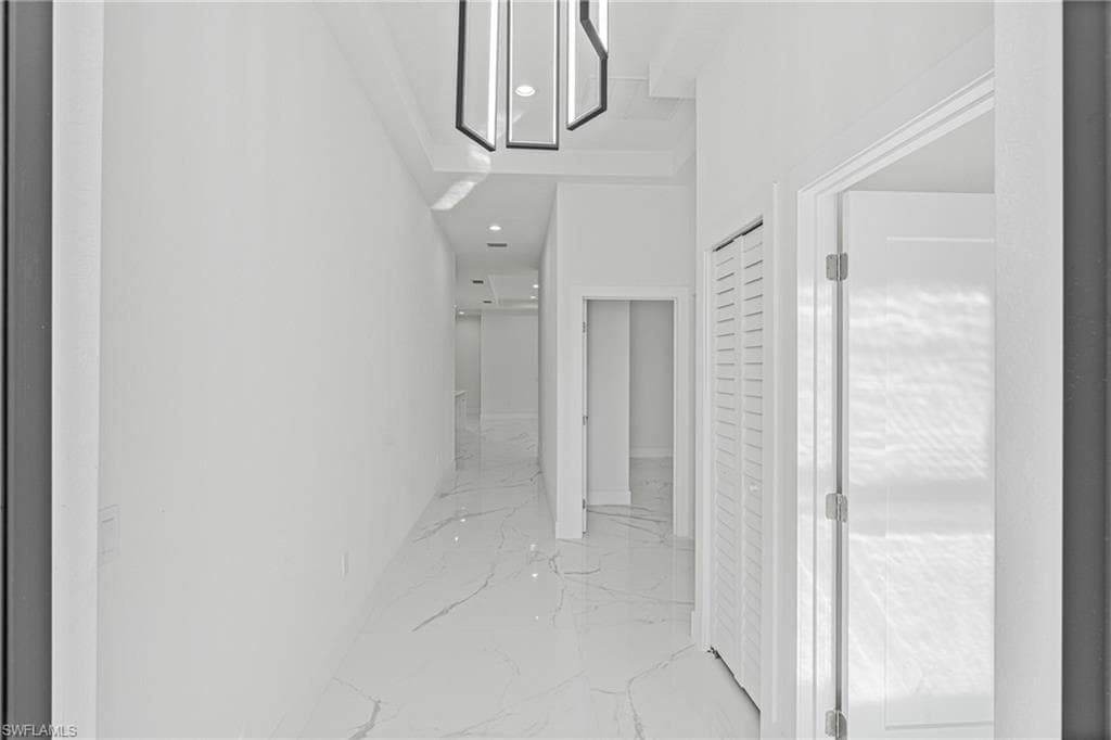 Corridor with light marble finish floors and recessed lighting