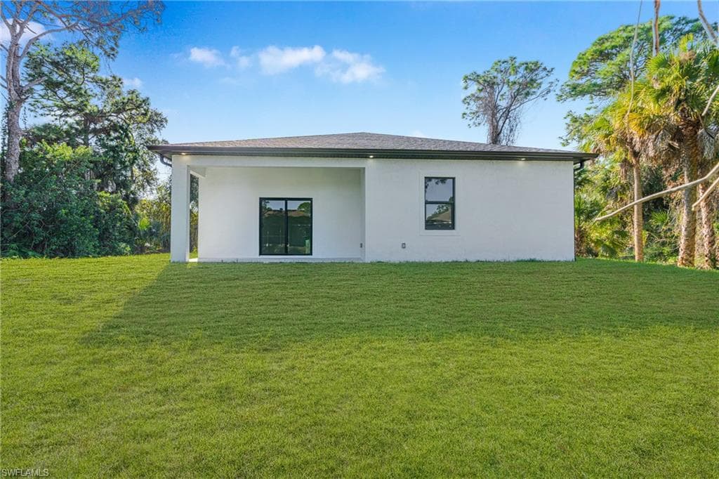 Rear view of property with a yard and stucco siding