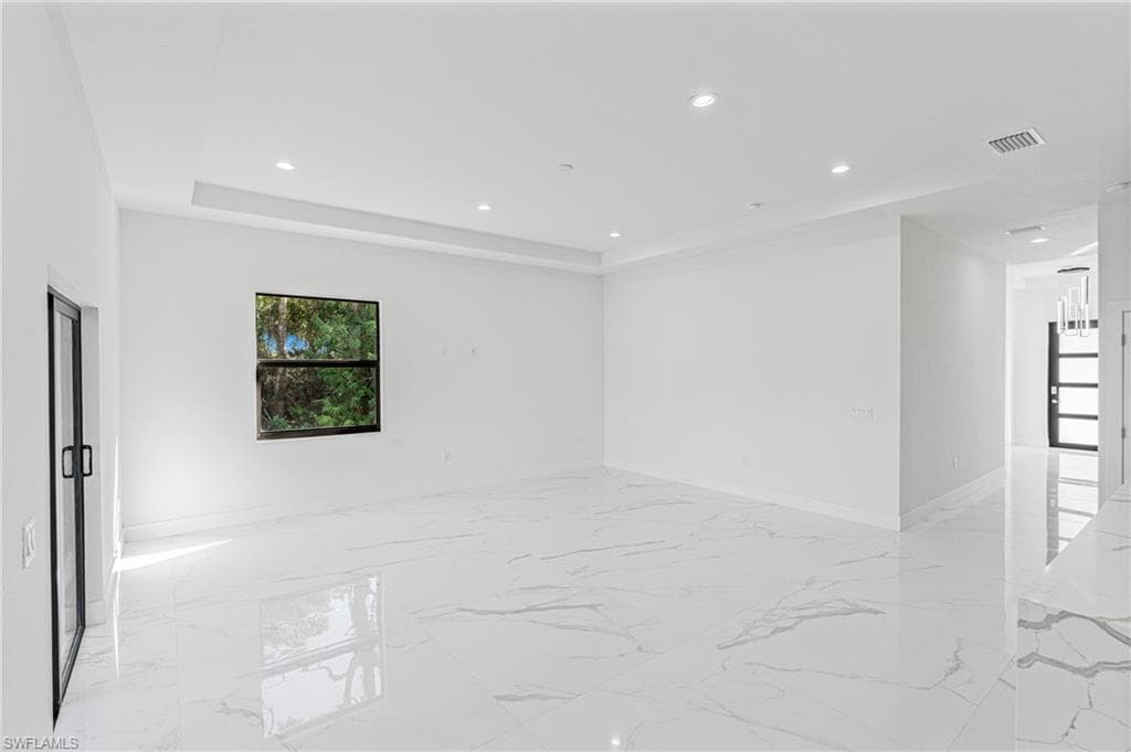 Unfurnished room with recessed lighting, light marble finish floors, and a raised ceiling