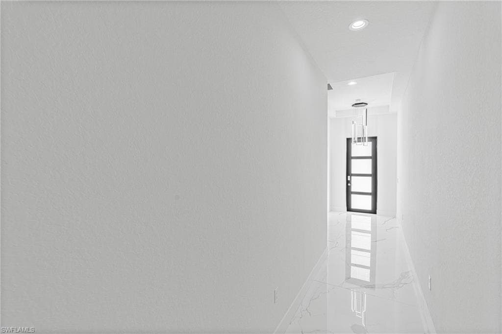 Hallway with marble tiled floors, recessed lighting, and a textured wall