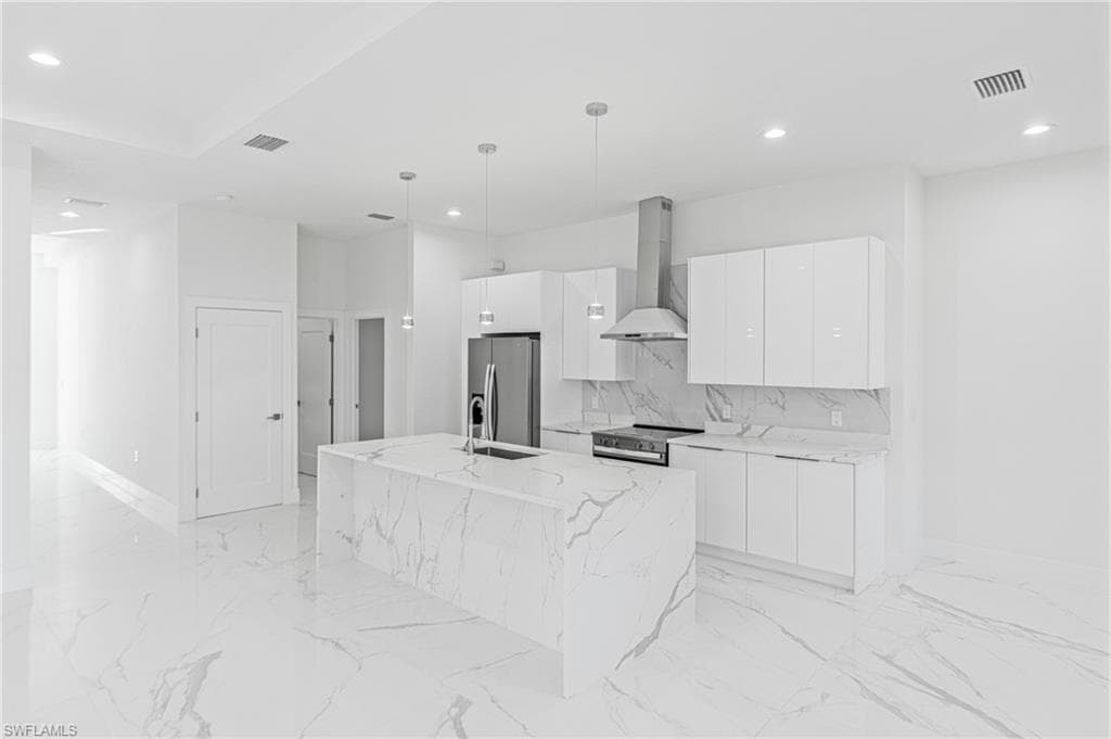 Kitchen with pendant lighting, wall chimney range hood, a center island with sink, stainless steel appliances, and modern cabinets