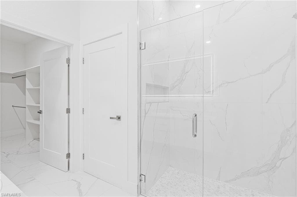 Bathroom with light marble finish flooring and a marble finish shower