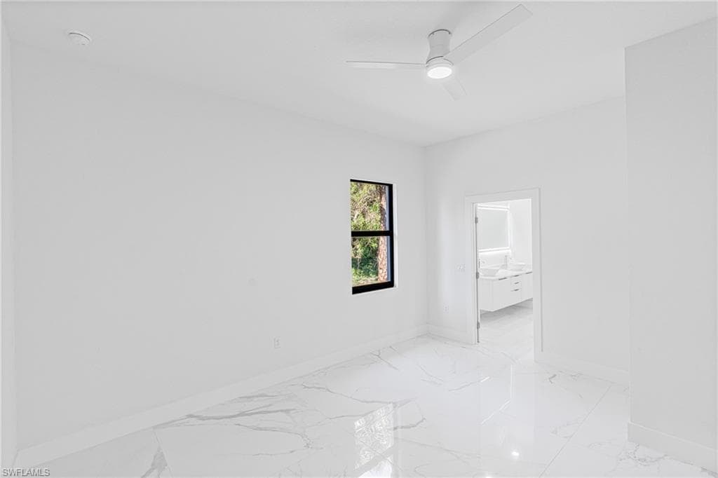 Empty room featuring a ceiling fan and light marble finish floors