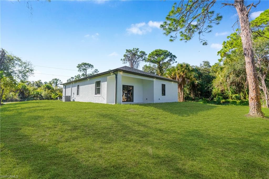 Rear view of property with a yard and stucco siding