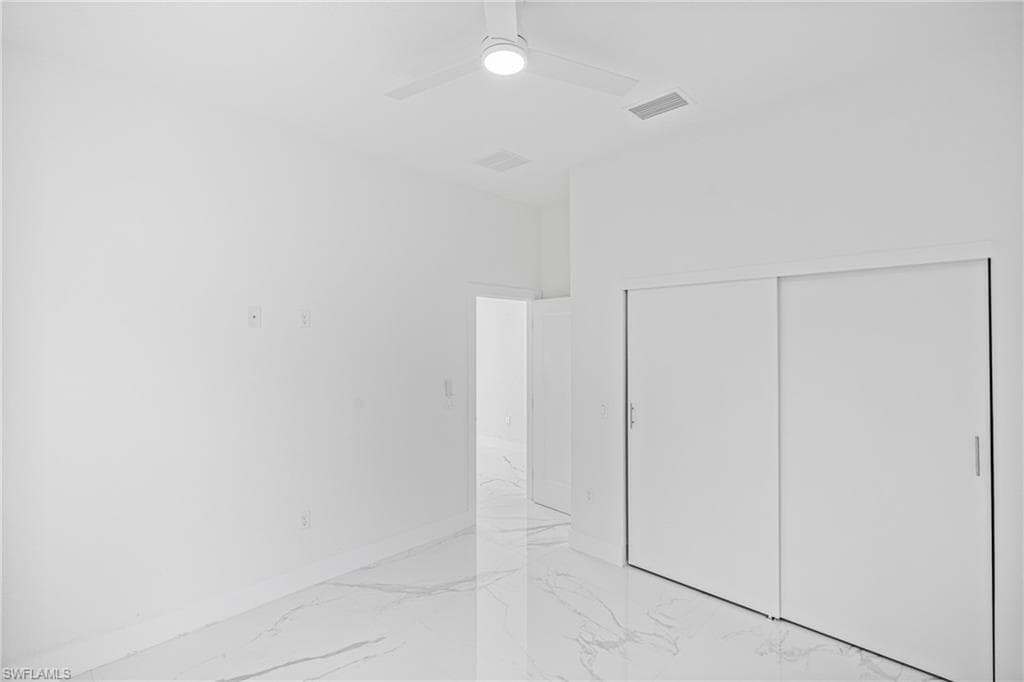 Spare room with light marble finish floors and a ceiling fan
