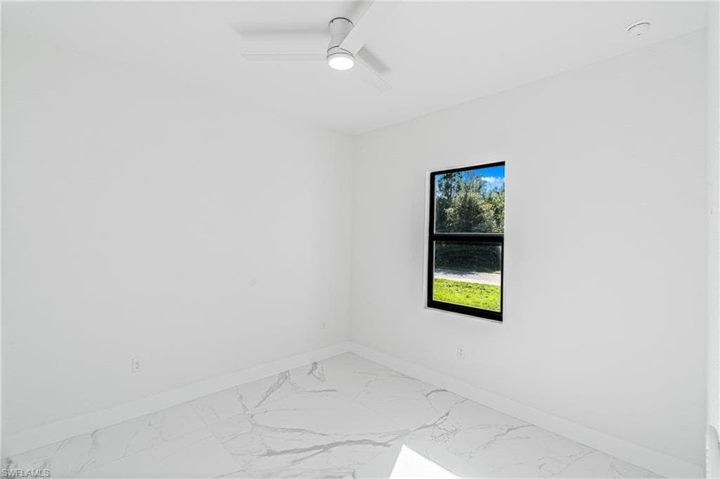 Unfurnished room with light marble finish flooring and a ceiling fan