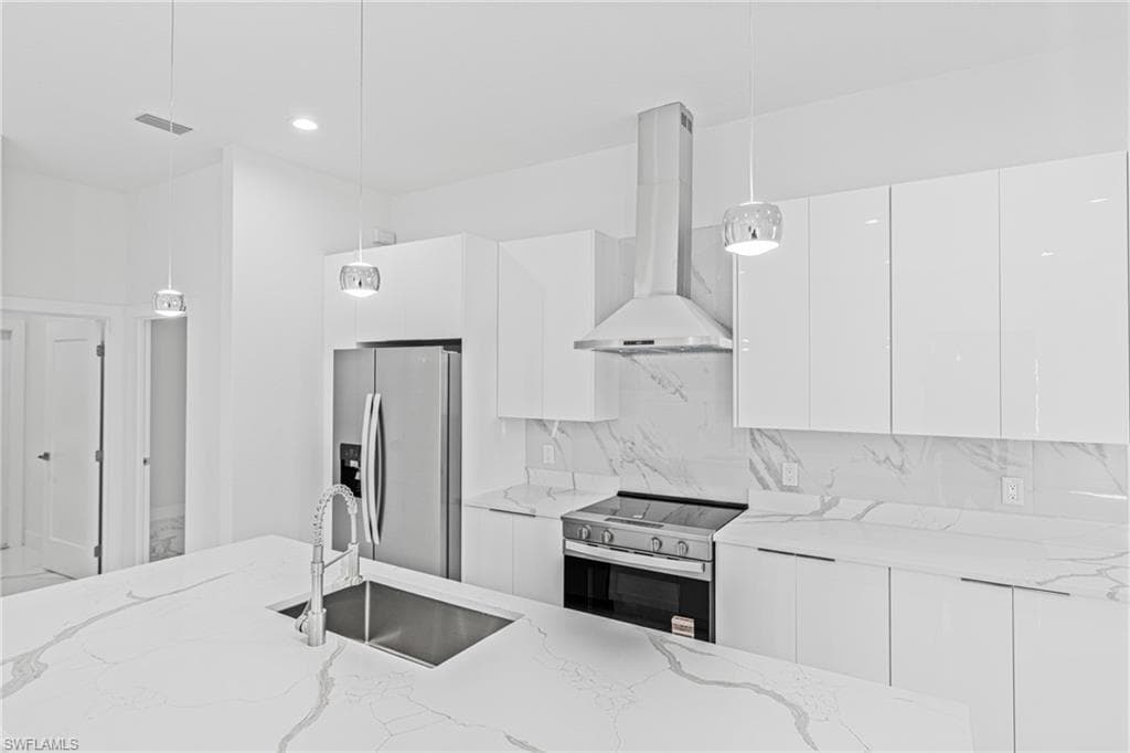 Kitchen with modern cabinets, decorative light fixtures, extractor fan, white cabinetry, and recessed lighting