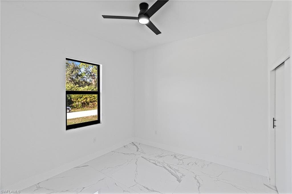 Empty room featuring light marble finish flooring and ceiling fan