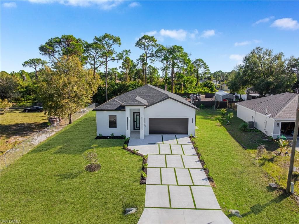 View of front of property featuring a front lawn, stucco siding, driveway, and a garage