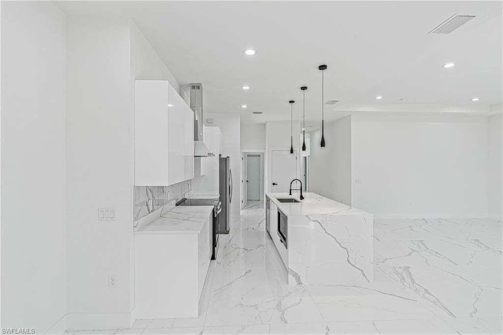 Kitchen featuring white cabinets, recessed lighting, light stone countertops, pendant lighting, and modern cabinets
