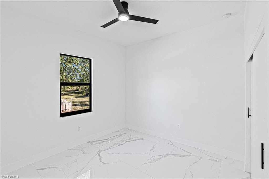 Unfurnished room with marble look tiles and ceiling fan