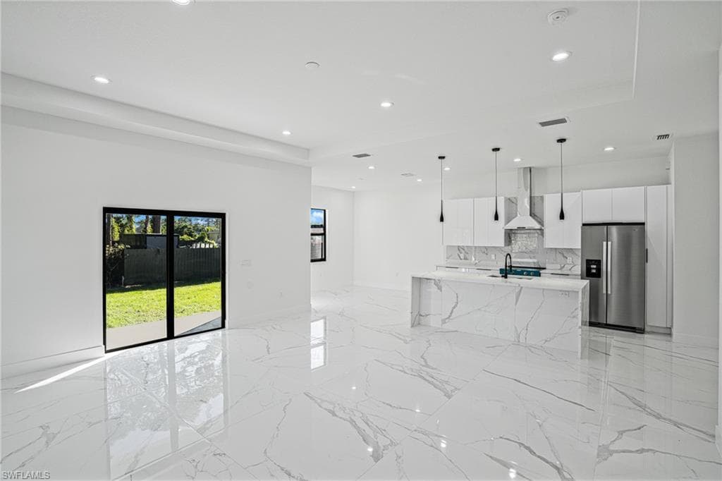 Unfurnished living room with light marble finish flooring, recessed lighting, and a raised ceiling