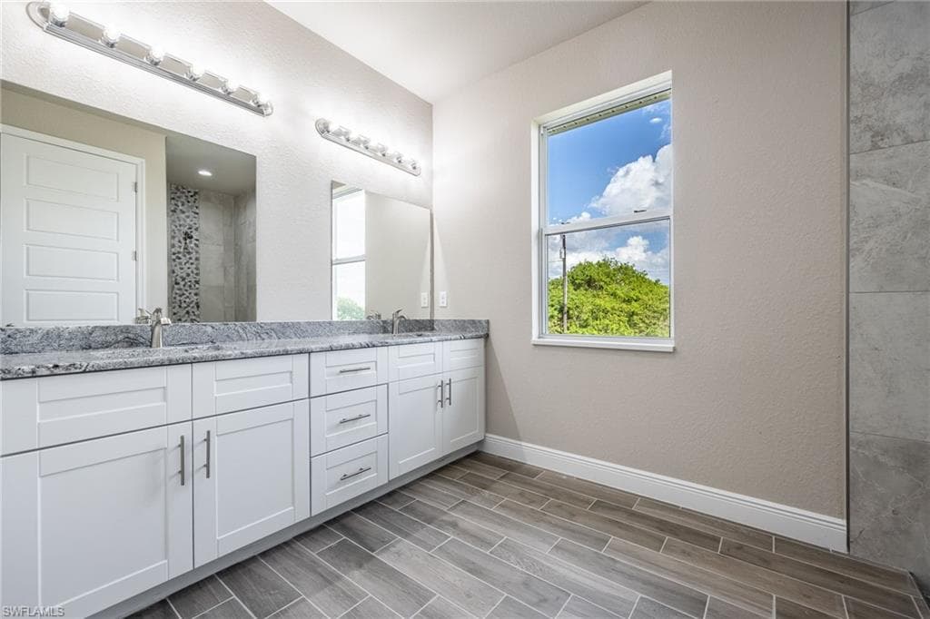 Bathroom with double vanity, a stall shower, wood finish floors, and a textured wall-Finishes may vary