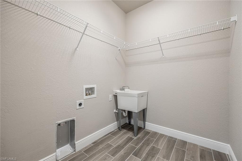 Laundry area featuring wood finish floors, hookup for a washing machine, hookup for an electric dryer, and a textured wall-Finishes may vary