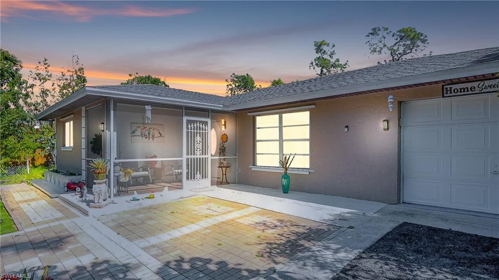Exterior entry at dusk with stucco siding and an attached garage
