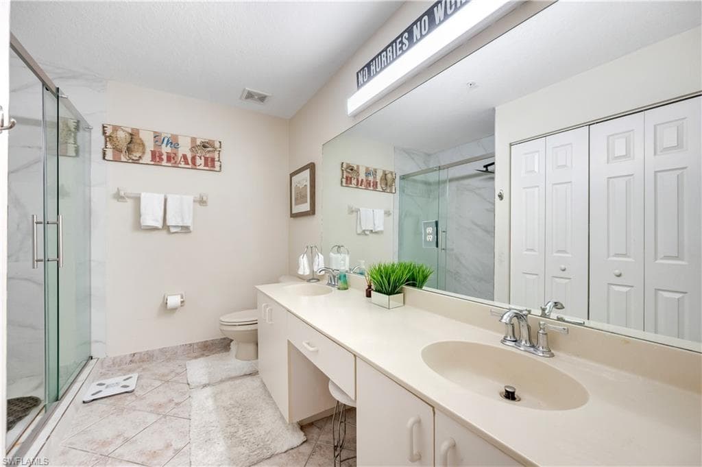 Bathroom with a closet, a marble finish shower, and double vanity