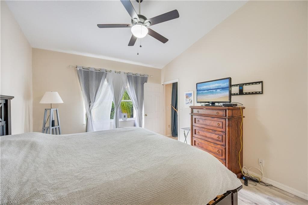 Bedroom featuring lofted ceiling, a ceiling fan, and light wood-style flooring
