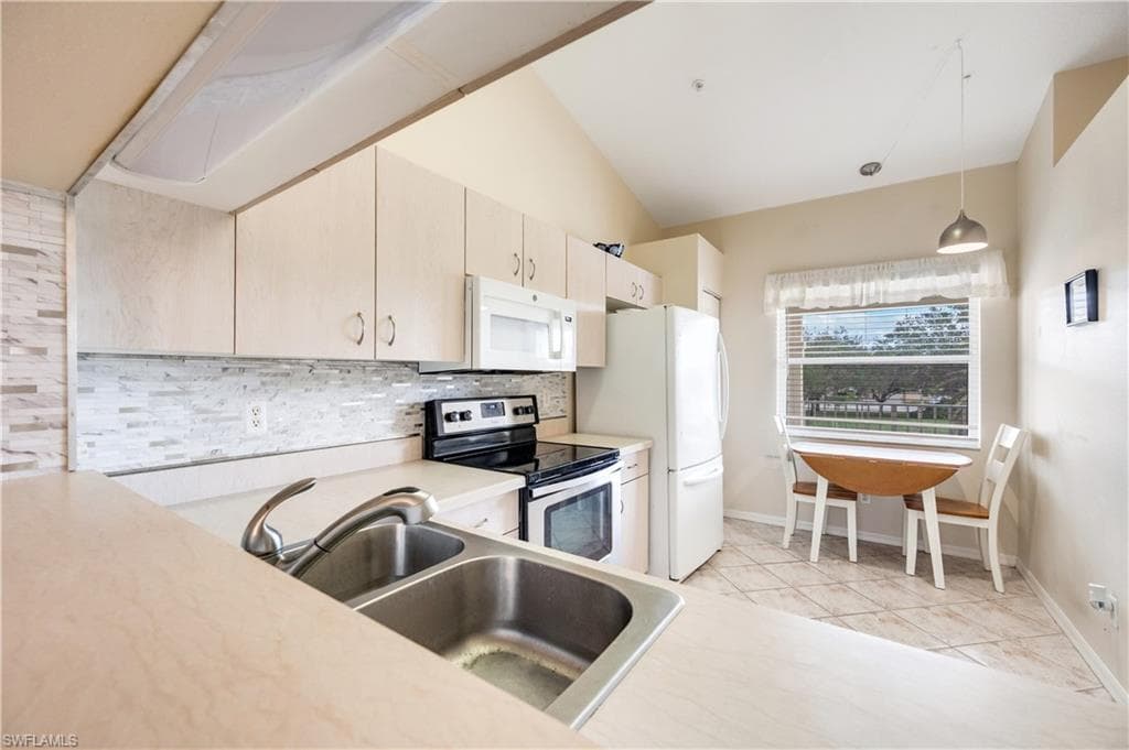 Kitchen with light countertops, stainless steel electric range oven, pendant lighting, tasteful backsplash, and white microwave