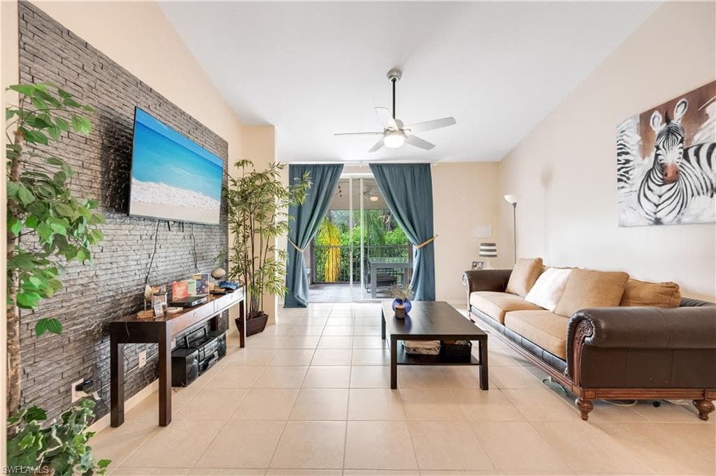 Tiled living area with a ceiling fan, brick wall, and an accent wall