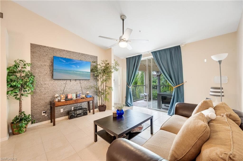 Tiled living area featuring vaulted ceiling and ceiling fan