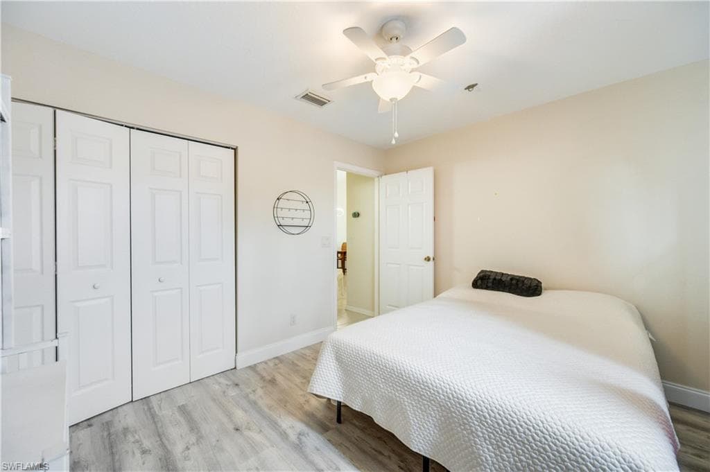 Bedroom with light wood-style flooring, ceiling fan, and a closet