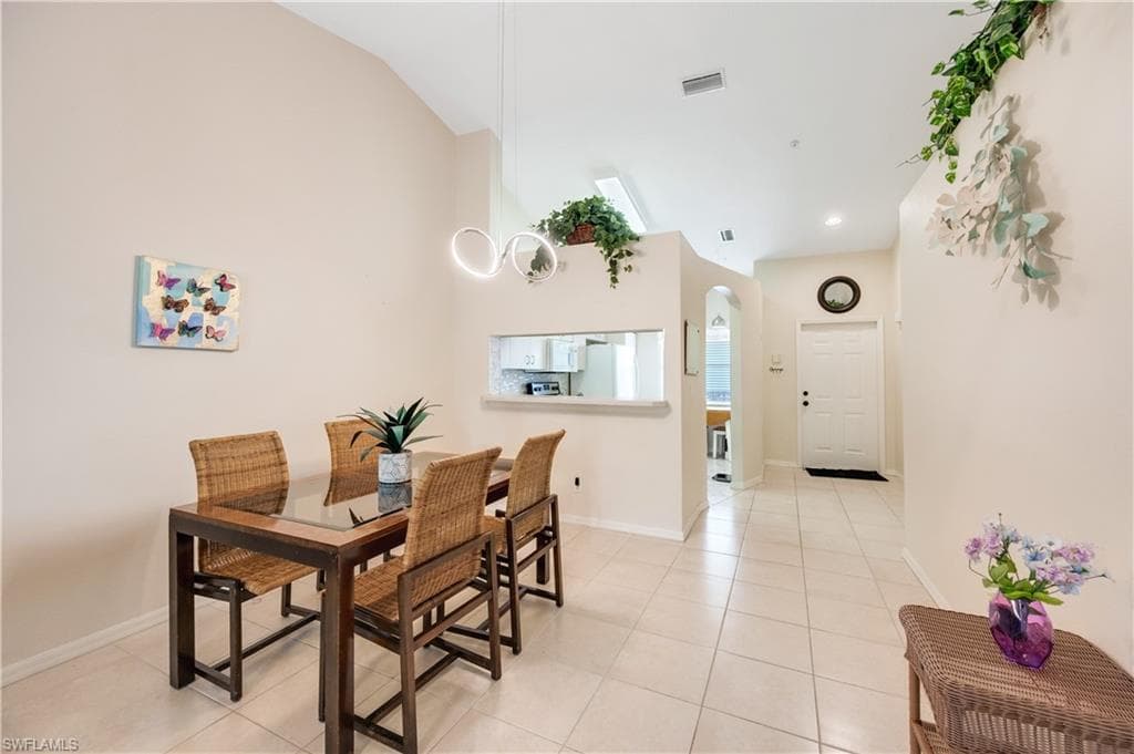 Dining area with arched walkways, light tile patterned flooring, and lofted ceiling