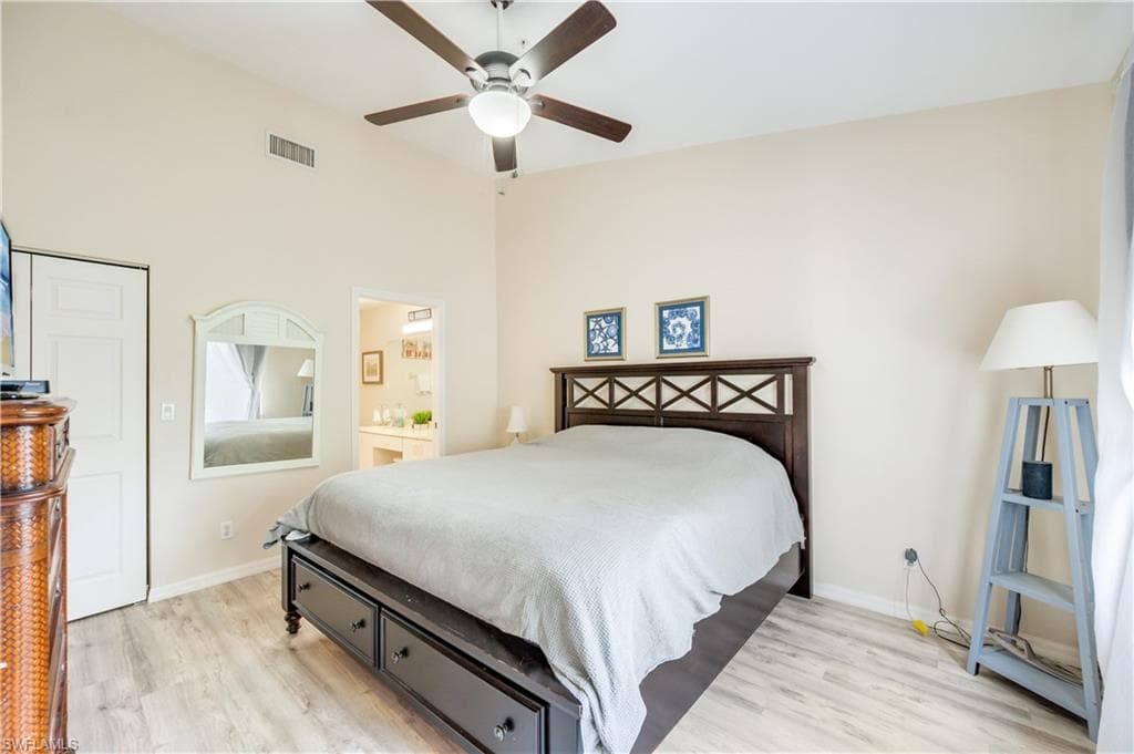 Bedroom with light wood finished floors, a ceiling fan, and ensuite bath