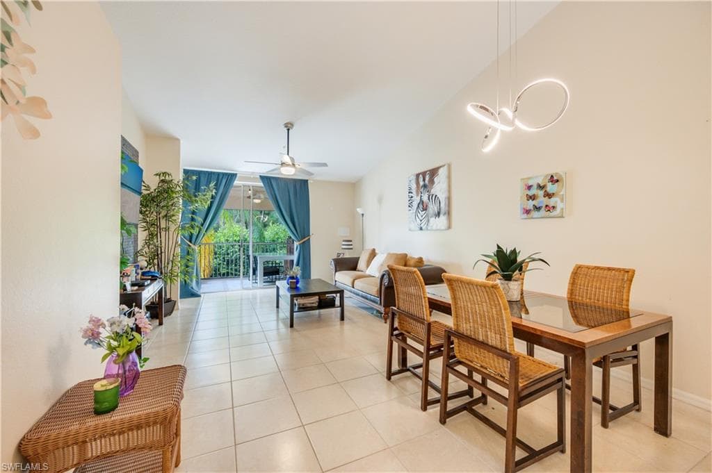 Dining area featuring ceiling fan, light tile patterned floors, and lofted ceiling