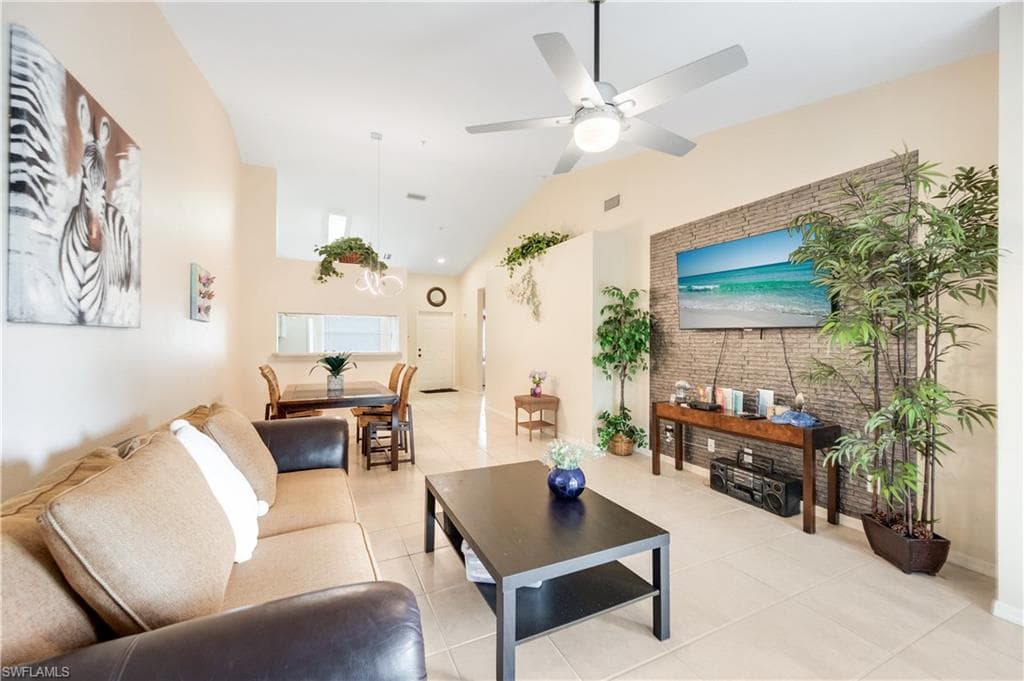 Living area with light tile patterned floors, a ceiling fan, and high vaulted ceiling