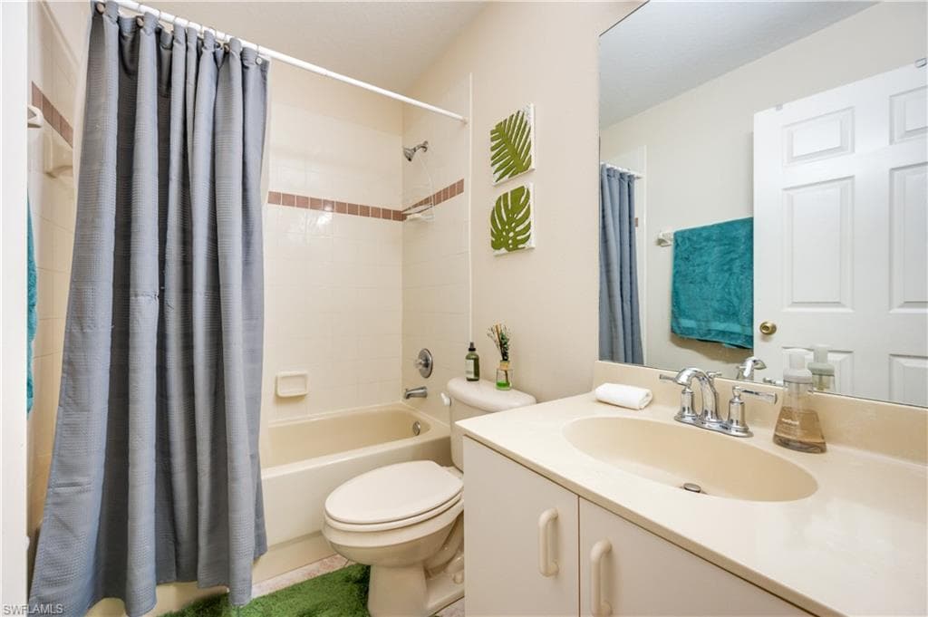 Bathroom featuring shower / bathtub combination with curtain and vanity