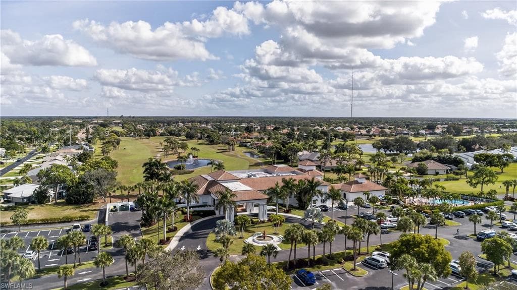 Aerial view of property and surrounding area with a golf course, a large body of water, and nearby suburban area